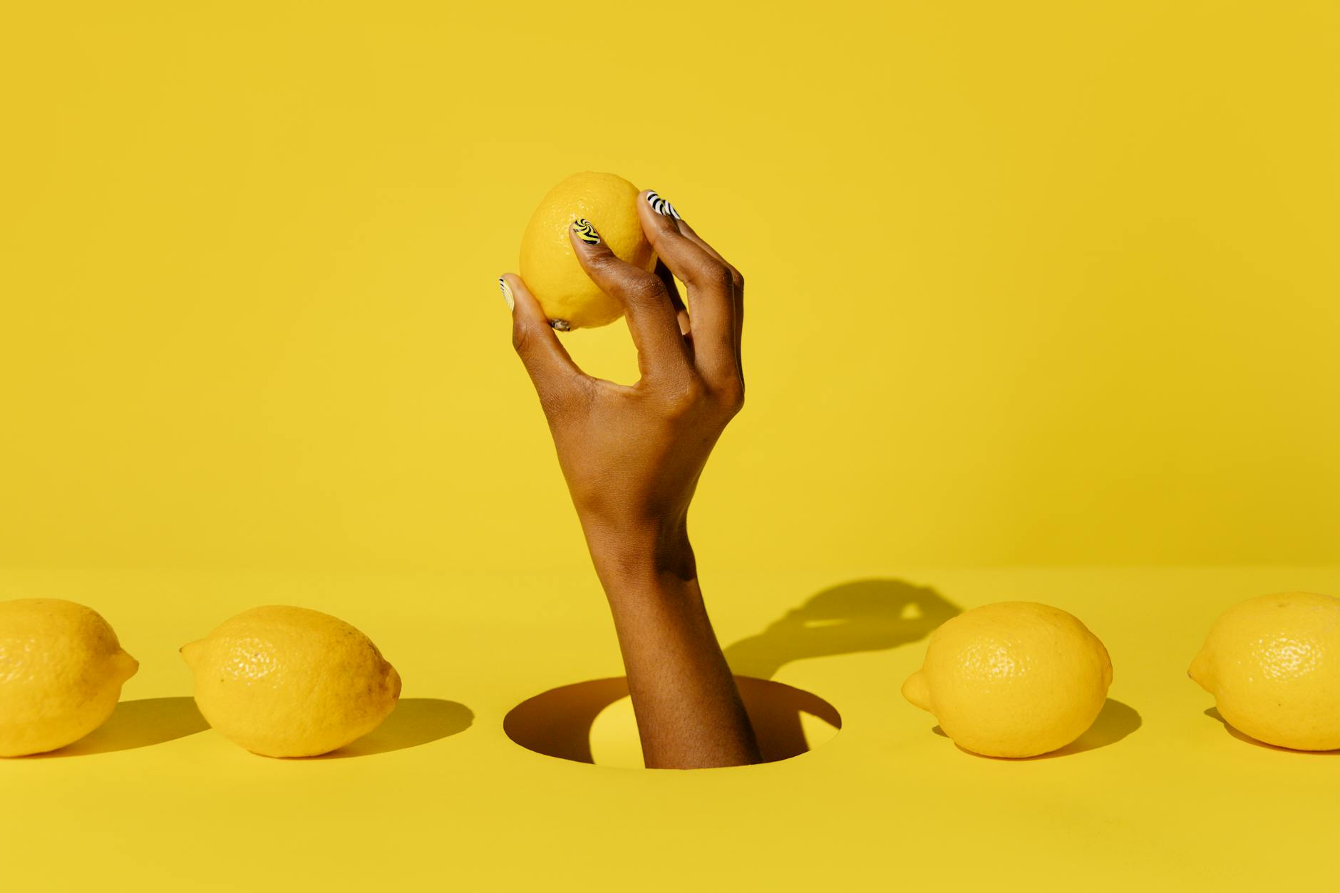 Hand holding a lemon against a vivid yellow background, symbolizing the bright, fresh sensation of lemon vibrator stimulation