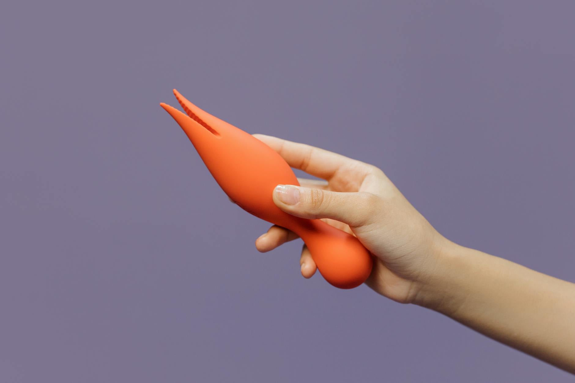 Hand holding a lemon-colored vibrator against a purple backdrop, demonstrating modern sensuality and intimate wellness.